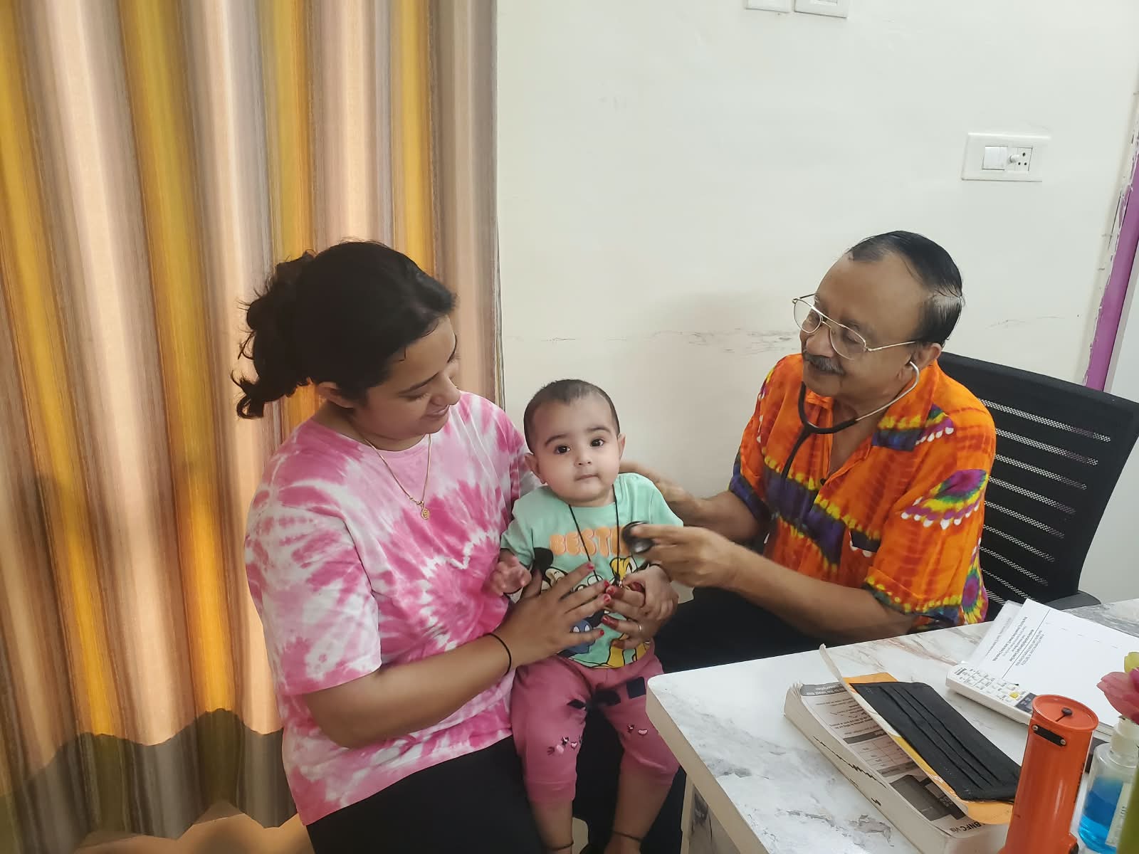 Dr. Atul Mohan examining a baby seated with their mother